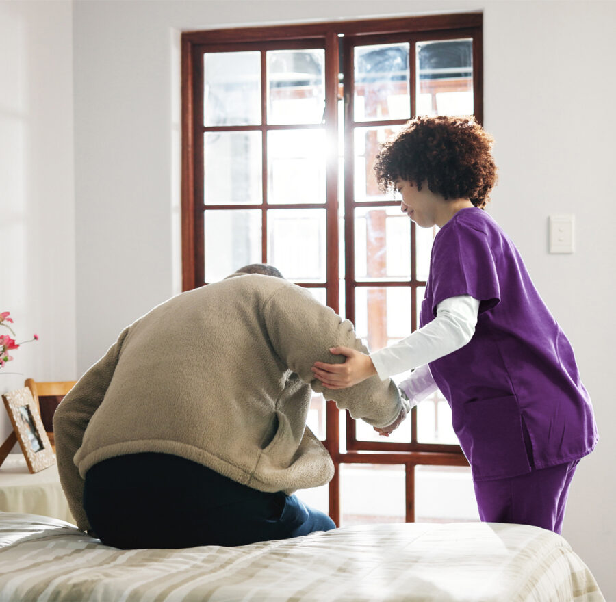 Caregiver helping an elderly person sit up.