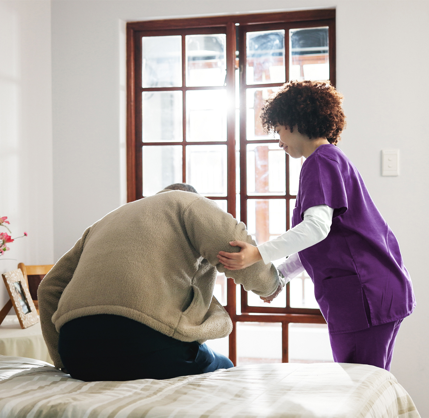Caregiver helping an elderly person sit up.